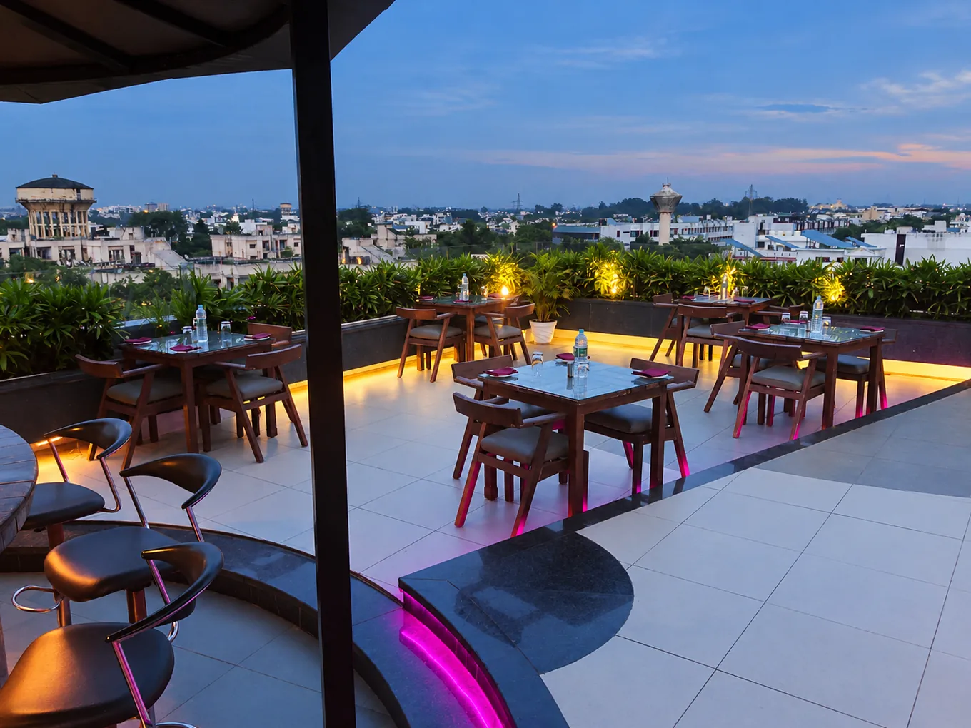 Set rooftop dining tables overlooking the city in the blue evening light