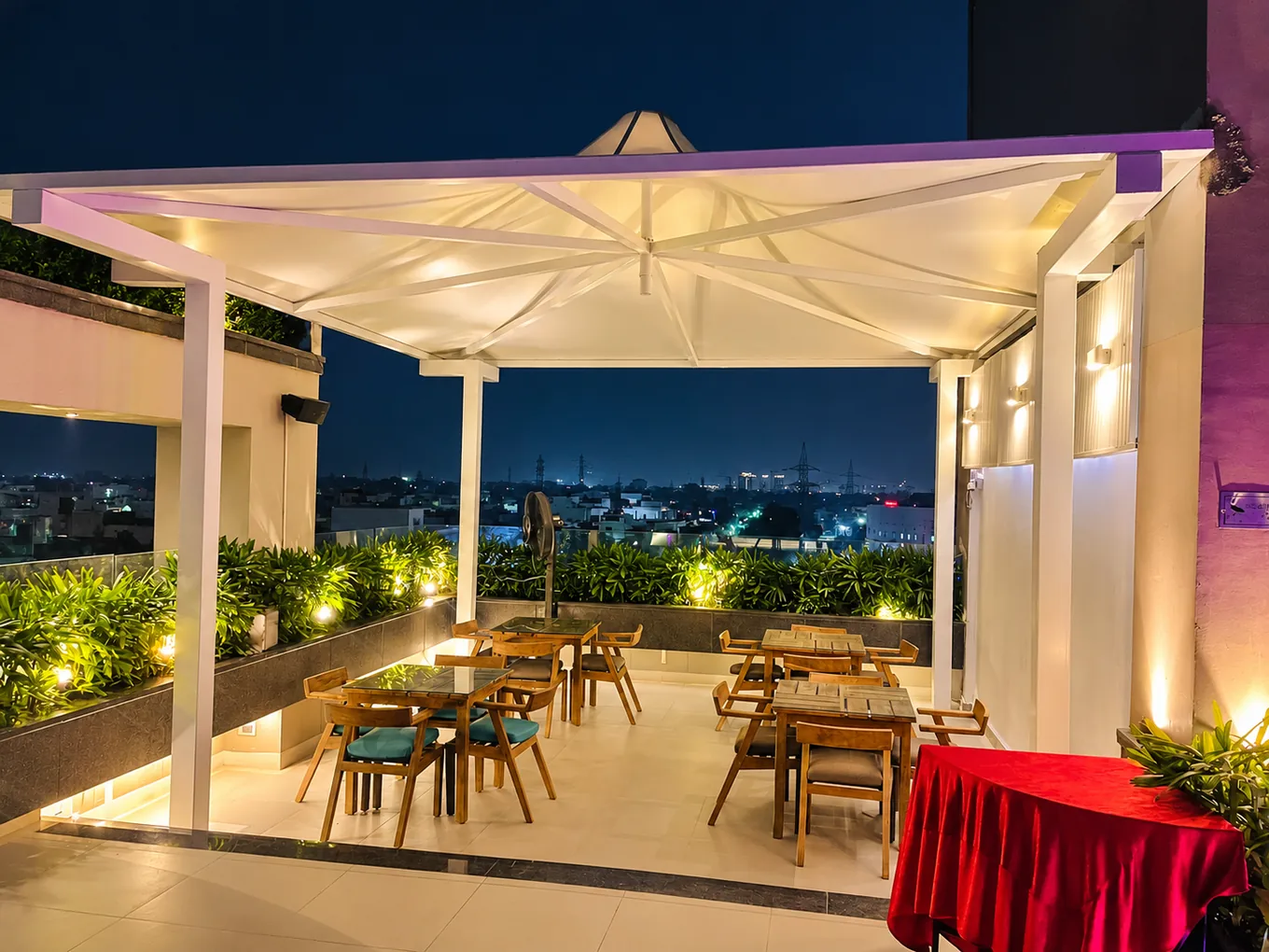 Wooden dining tables beneath a white rooftop canopy at night